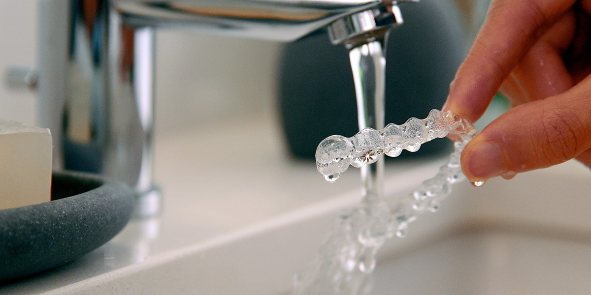 Zahnschiene unter einem Wasserhahn reinigen